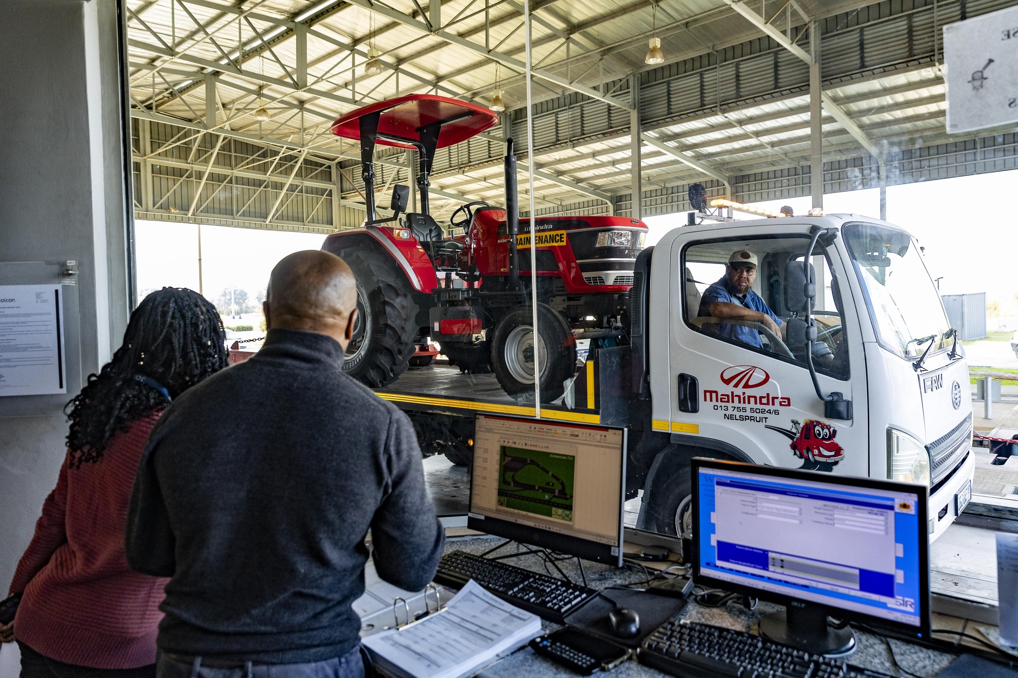 Two people looking at an item on a truck