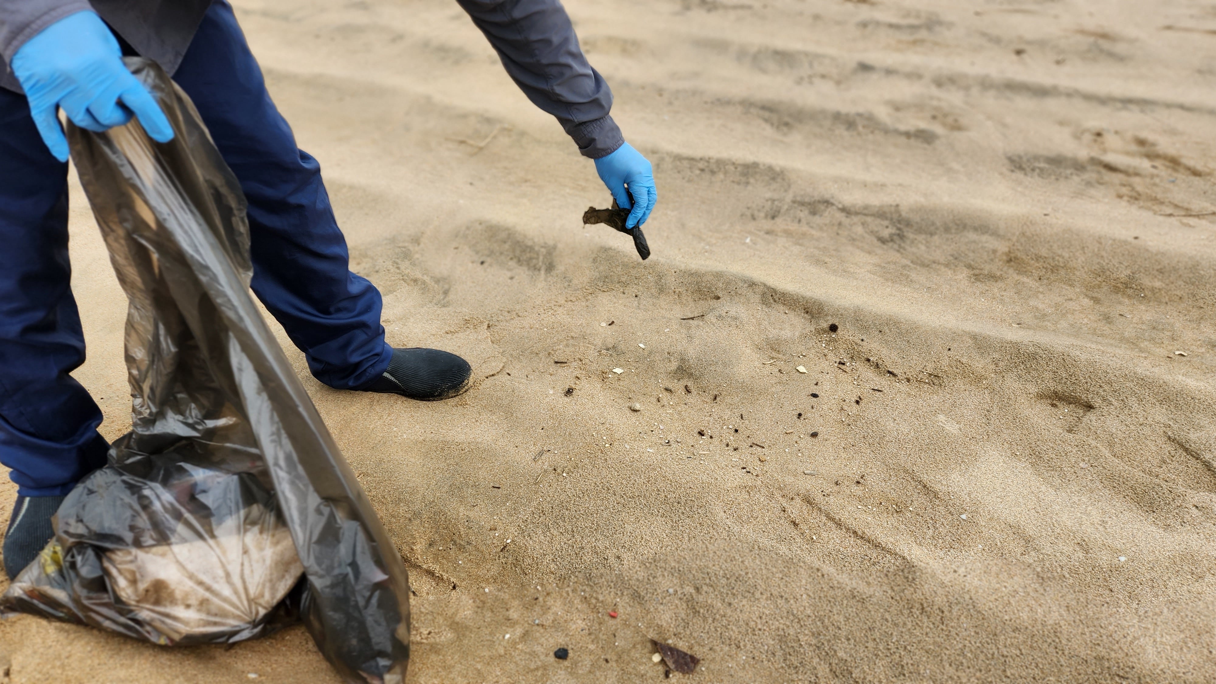 Person picking up items on beach