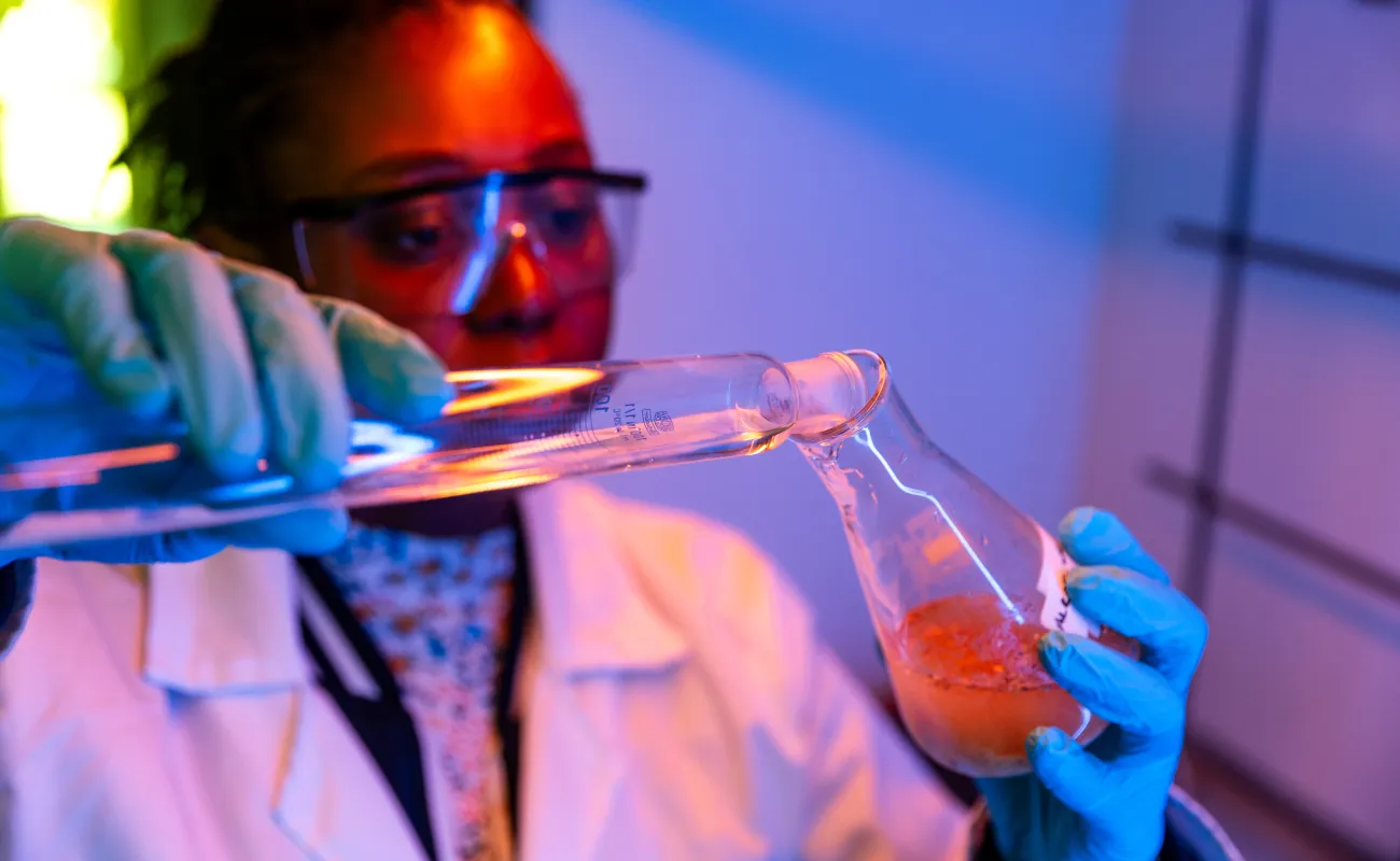 lady pouring liquid in a beaker